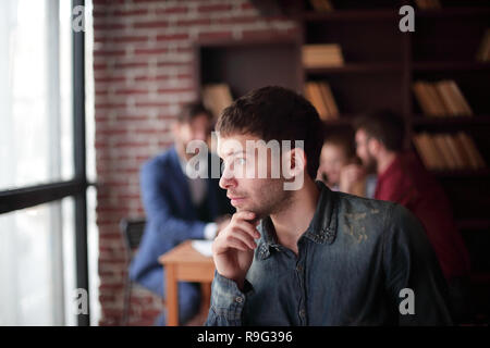 pensive young designer looking out the office window. Stock Photo