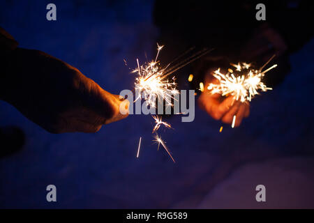 hands of elderly couple holding sparkles celebrating New Year Stock Photo
