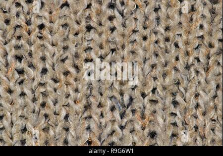 Close-up swatch of coarse woolen knit texture from a tan-colored cardigan. Stock Photo