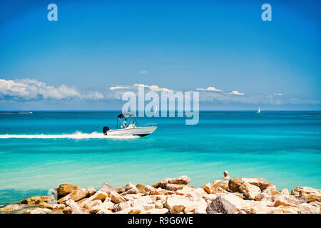 Motor boat floating fast on azure sea water on blue sky on sunny day. Summer vacation and travelling concept. Stock Photo