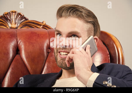 Man or businessman smile and talk on smartphone on sofa. Business communication concept. Entrepreneurship, new technology, modern life. Stock Photo