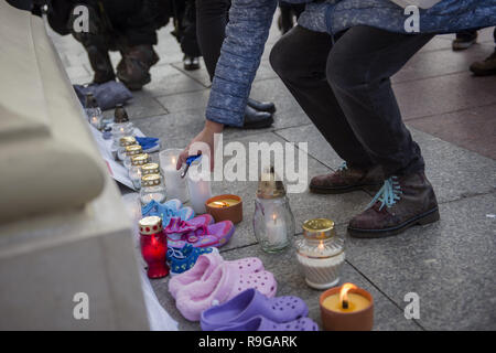 Warsaw, Poland. 23rd Dec, 2018. Protesters are seen lighting candles during the protest.The Nationwide Women's Strike (OgÃ³lnopolski Strajk Kobiet) organized the campaign called ''We accuse pedophiles''. At the gates of churches around Poland, children's shoes were hanged and candles were lightened to commemorate the victims of sexually abused children by Catholic priests. In Warsaw, the action took place in the Old Town's church of St. Anne. Credit: Attila Husejnow/SOPA Images/ZUMA Wire/Alamy Live News Stock Photo