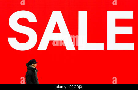 A woman is seen walking past a large SALE sign at H M store on London Oxford