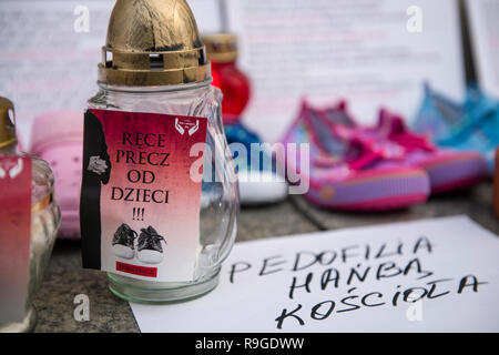 Warsaw, Poland. 23rd Dec, 2018. Kids shoes, candles and placards are seen on the floor during the protest. The Nationwide Women's Strike (Ogólnopolski Strajk Kobiet) organized the campaign called 'We accuse pedophiles'. At the gates of churches around Poland, children's shoes were hanged and candles were lightened to commemorate the victims of sexually abused children by Catholic priests. In Warsaw, the action took place in the Old Town's church of St. Anne. Credit: SOPA Images Limited/Alamy Live News Stock Photo