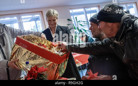 Hamburg, Germany. 24th Dec, 2018. Kirsten Fehrs, bishop of the Evangelische Nordkirche, distributes poinsettias to visitors in the Day Care Center (TAS) for the homeless on Christmas Eve, who are also invited to a Christmas dinner here. Credit: Markus Scholz/dpa/Alamy Live News Stock Photo