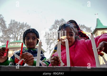 Kashmiri Christian kids light candles in front of the statue of Virgin Mary (not pictured ) outside the Holy Family Catholic Church during Christmas in Srinagar, Indian administered Kashmir. Amid a biting cold wave in the state, the Christian community of the valley on Tuesday celebrated the Christmas; the birthday of Jesus Christ, with zest and gaiety in Srinagar. Among those who prayed were tourists from different parts of the country who joined the locals on the auspicious day and prayed for peace in Kashmir and rest of the world. Stock Photo