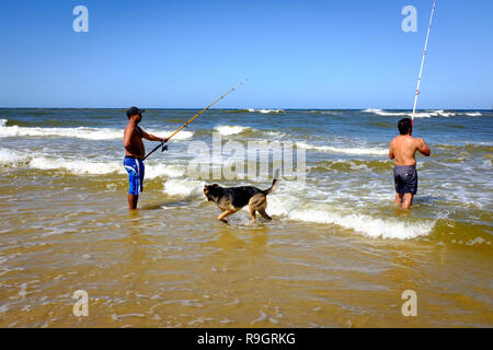 Uruguay: Uruguay, La Floresta, small city and resort on the Costa de Oro (Golden Coast). Two anglers and their dog (a German shepherd) in the waves. Stock Photo