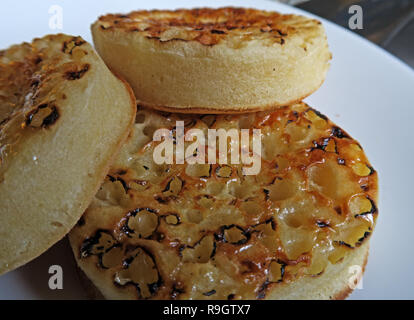 Three toasted buttered English Crumpets on a white plate Stock Photo