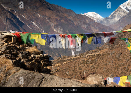 Nepal, Namche Bazar, prayer flags from rough rocky chorten, Kongde Ri and Pachermo peak behind Stock Photo