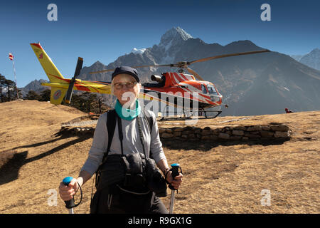 Nepal, Everest Base Camp Trek, Everest View Hotel, trekker resting by helipad beside Shree Airlines AS350 b3e Helicopter