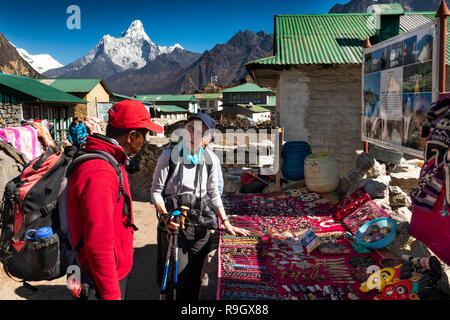 Nepal, Everest Base Camp Trek, Khumjung village, trekker and Sherpa Guide at small tourist souvenir stall outside local guest house lodge Stock Photo
