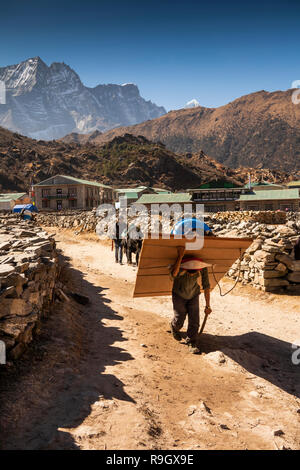 Nepal, Everest Base Camp Trek, Khumjung village, porter carrying heavy load of plywood on back Stock Photo