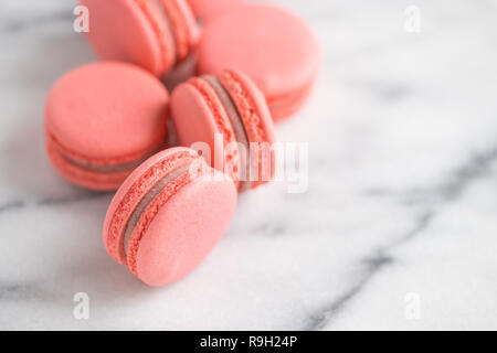 Coral cakes macarons or macaroons on white marble. Stock Photo
