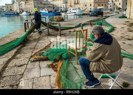 Fisherman repairing nets after fishing. Trani Stock Photo