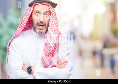 Senior arab man wearing keffiyeh over isolated background afraid and shocked with surprise expression, fear and excited face. Stock Photo