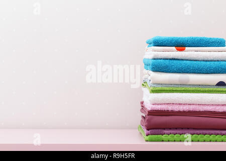 On the dresser there is a stack of clean ironed bed linen and folded colored towels. Stock Photo