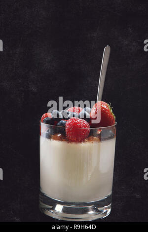 Panakota creamy Italian dessert in a glass beaker with berries on a dark background. Stock Photo