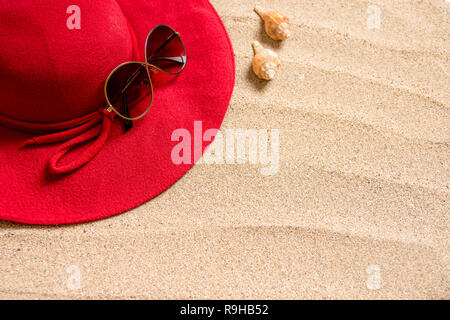 red hat on sandy beach with sunglasses, seashells and copy space for text. Stock Photo