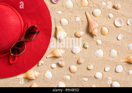 red hat on sandy beach with sunglasses, seashells and copy space for text. Stock Photo