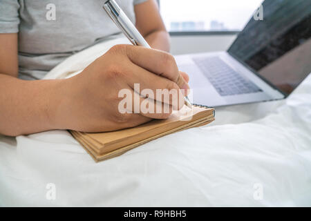 Man hands with pen writing on notebook in the hotel Stock Photo