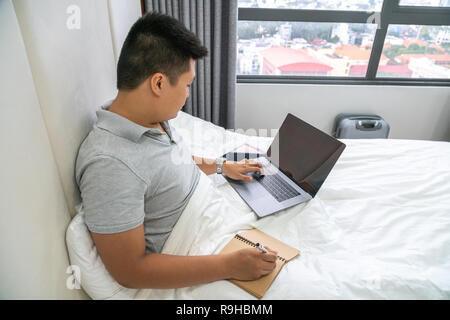 Young man search information on Internet and take notes Stock Photo