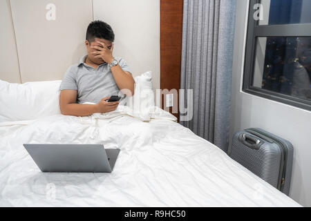 Asian businessman reading bad news on smart phone in business trip Stock Photo