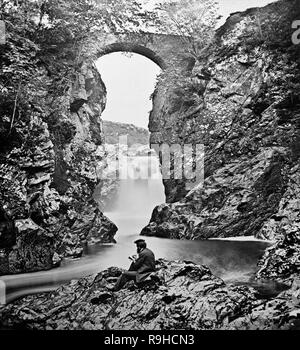 A late Victorian photograph showing a man sitting beside the upper part of the Fall Of Foyers in Scotland.The Fall of Foyers (Scottish Gaelic: Eas na Smùide, meaning the smoking falls) is a waterfall on the River Foyers, which feeds Loch Ness, in Highland, Scotland, United Kingdom. The waterfall has 'a fine cascade', having a fall of 165 feet. It is located on the lower portion of the River Foyers. The river enters Loch Ness on the East side, North-East of Fort Augustus.