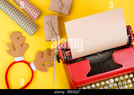 Holidays concept - red typewriter with blank craft paper, gift boxes on yellow background Stock Photo