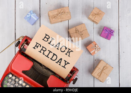 Sale concept - red typewriter with craft paper with text "Black friday", gift boxes on white wooden background Stock Photo