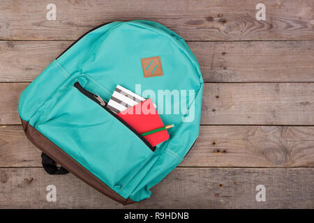 Backpack and school supplies: notepad, pencil on brown wooden table Stock Photo