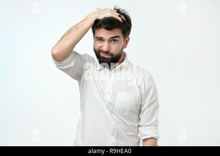 Hispanic man with beard looking with puzzled expression, scratching head, being clueless Stock Photo