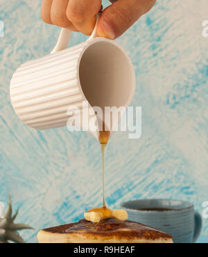 Pancakes stack pouring marple syrup. Little jug in a man's hand. Breakfast. coffee cup. side view. Stock photo Stock Photo