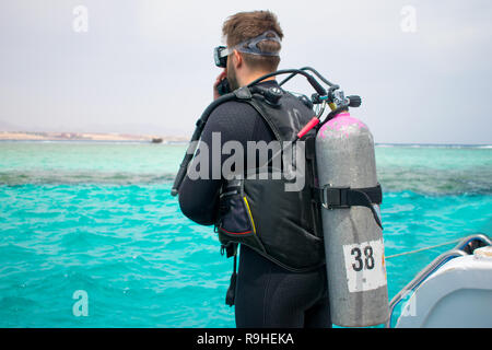 A diver in diving gear is preparing to dive. a man in a wet suit, with an aqualung,mask and a balloon, jumps into the water. scuba. scubadiving. Stock Photo