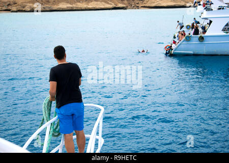 a sailor with a rope stands on the bow of the yacht and waits for another yacht for fastening, mooring Stock Photo