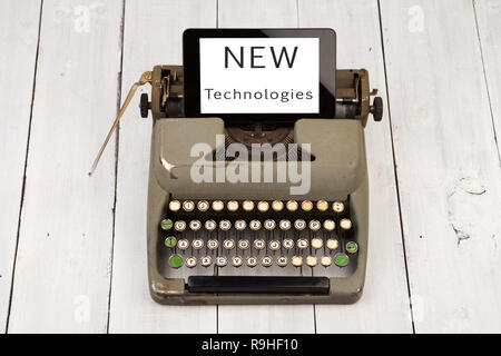 Concept of technology progress - old typewriter and new tablet pc with words 'NEW Technologies' on wooden background Stock Photo