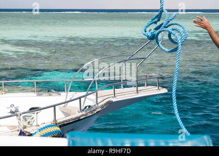 yacht mooring. Supplying a rope to a nearby yacht for its mooring. view of the yachts bow against the azure sea and the coral reefs. Stock Photo