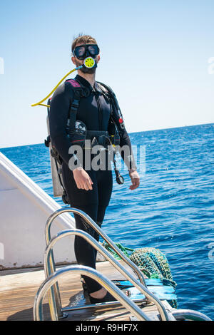 A diver in diving gear is preparing to dive. a man in a wet suit, with an aqualung,mask and a balloon, jumps into the water. scuba. scubadiving. Stock Photo