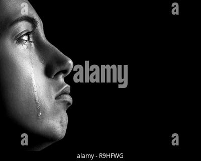 sad woman crying, looking up on black background with copy space, closeup portrait, profile view, monochrome
