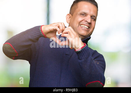 Middle age arab man over isolated background smiling in love showing heart symbol and shape with hands. Romantic concept. Stock Photo