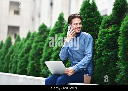 Young attractive guy who is smiling looking at his laptop screen during video call. Young man using laptop. Stock Photo