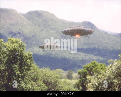 Two unidentified flying objects over a forest with trees and mountains behind. Stock Photo