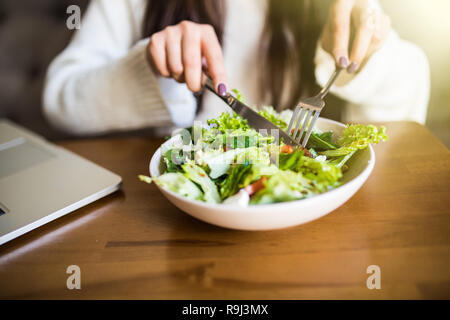 Close up attractive woman hand holding fork and spoon to eating vegetable salad at lunch in cafe. Stock Photo