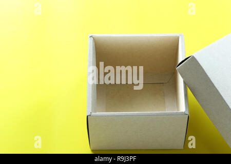 Empty brown paper box rests on a yellow paper floor and have copy space for design in your Christmas work concept. Stock Photo