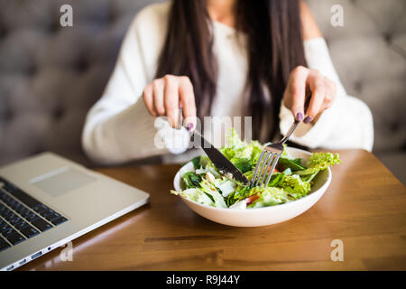 Close up attractive woman hand holding fork and spoon to eating vegetable salad at lunch in cafe. Stock Photo