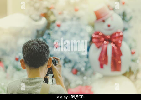 Photographer man take photo of decorated Christmas tree and a snowman. Stock Photo