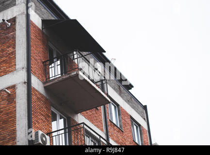 Part of a modern multi-storey building with windows and balconies on the white sky background Stock Photo