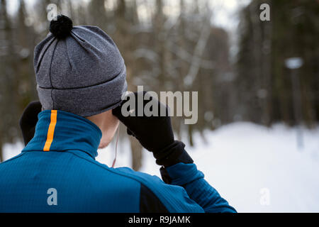 Portrait of a runner from the back wearing headphones and preparing to run in the winter forest Stock Photo