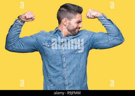 Young handsome man over isolated background showing arms muscles smiling proud. Fitness concept. Stock Photo