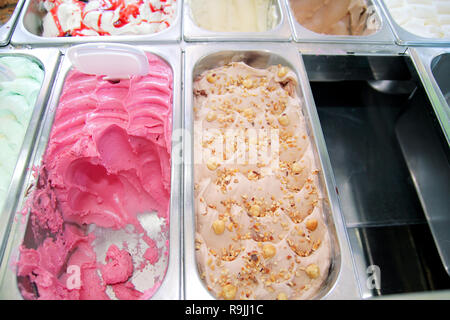 Bar with many flavors of delicious ice cream for sale. Fridge with creamy of hazelnut flavors, raspberry and cherry in serving steel container. Stock Photo
