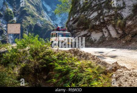 Tourist vehicle on sightseeing tour travel through dangerous mountain road affected by landslide near Binsar Uttarakhand India. Stock Photo